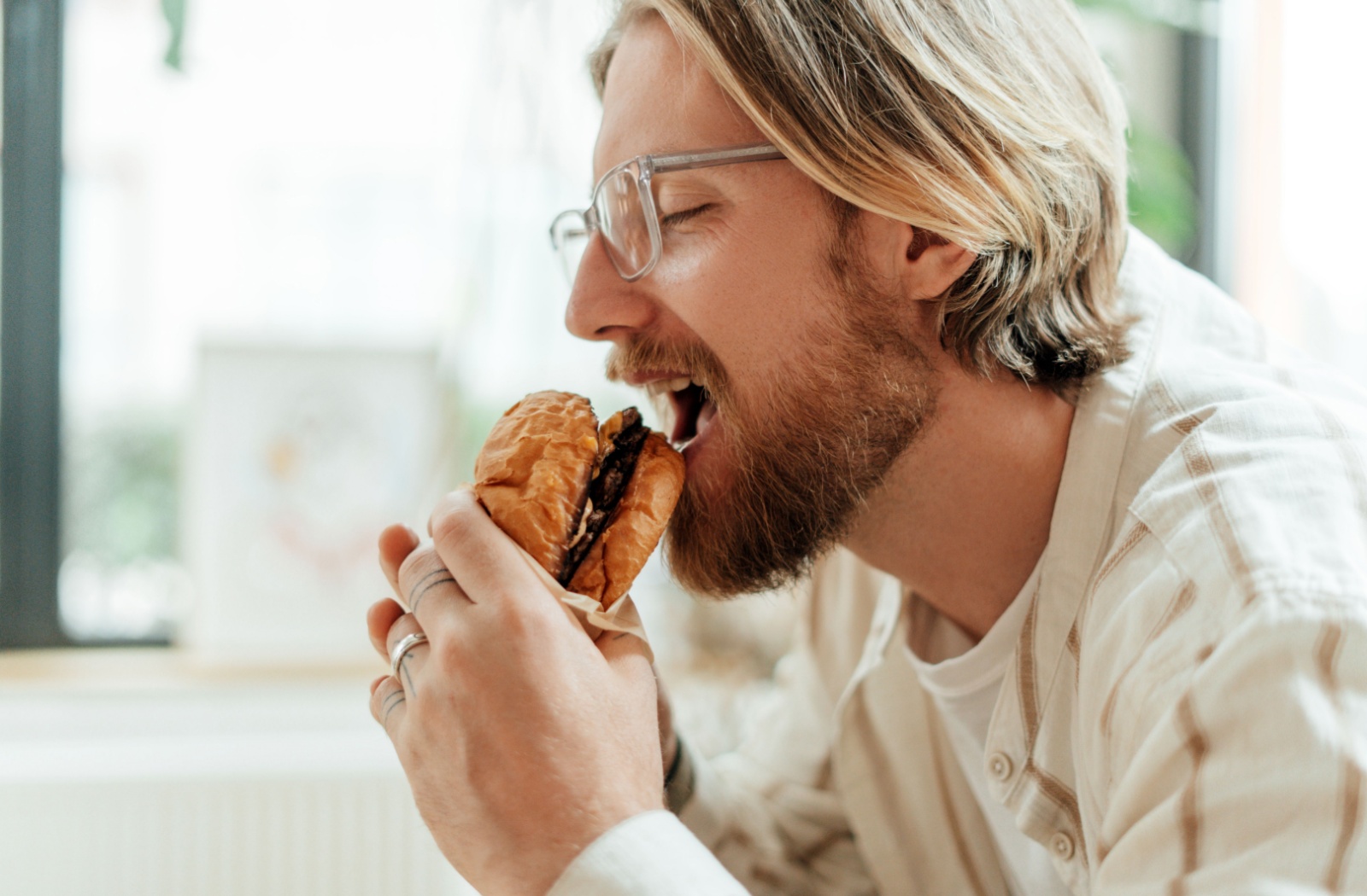 A person taking a bite of a hamburger after getting a dental cleaning
