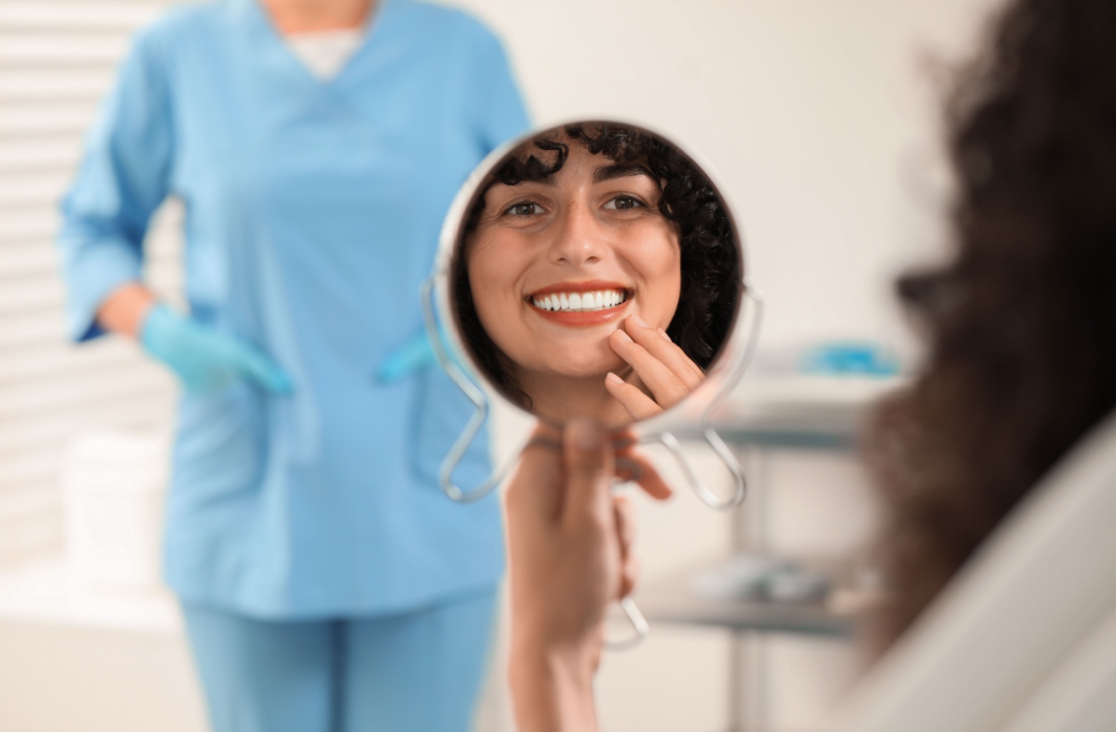 A person looks in a mirror at their teeth at the dentist