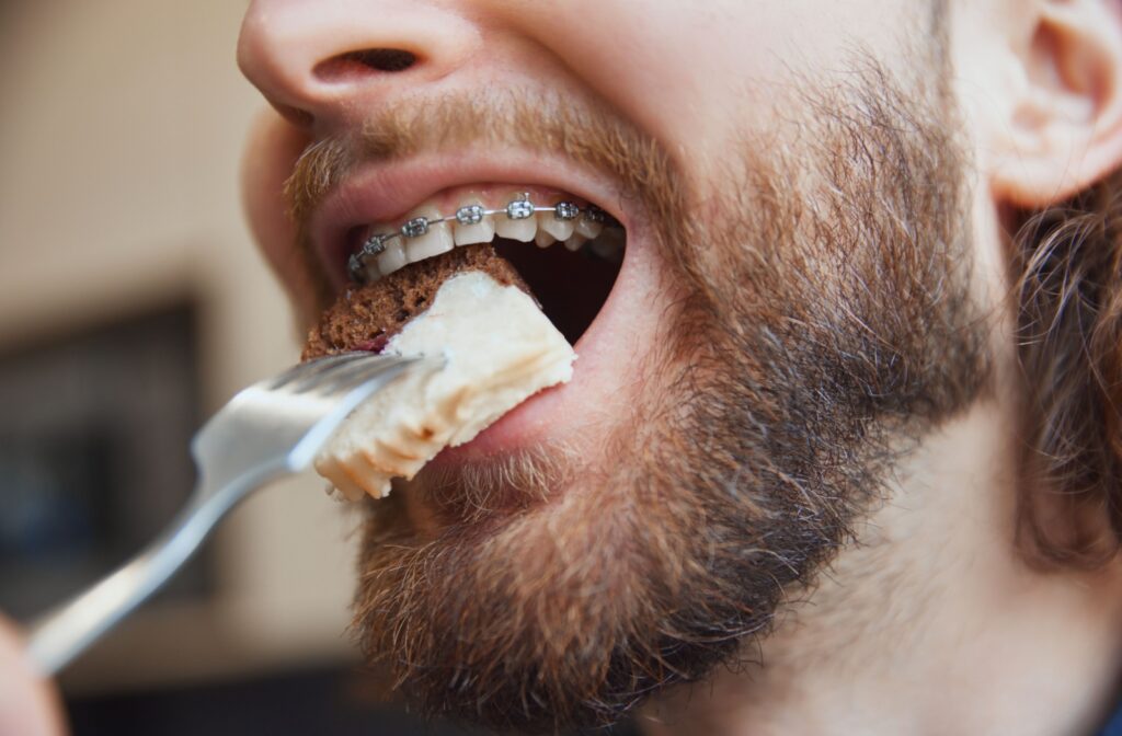 A person with braces eating a slice of cake