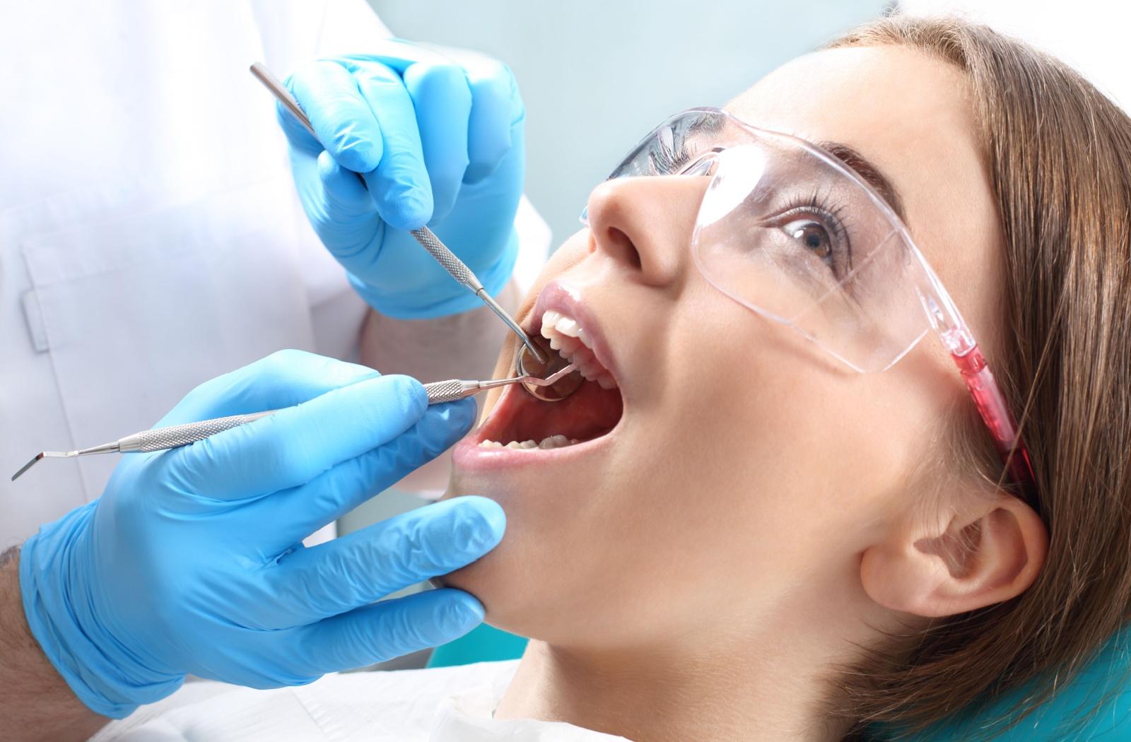 A young dental patient getting their teeth examined during a routine dental exam