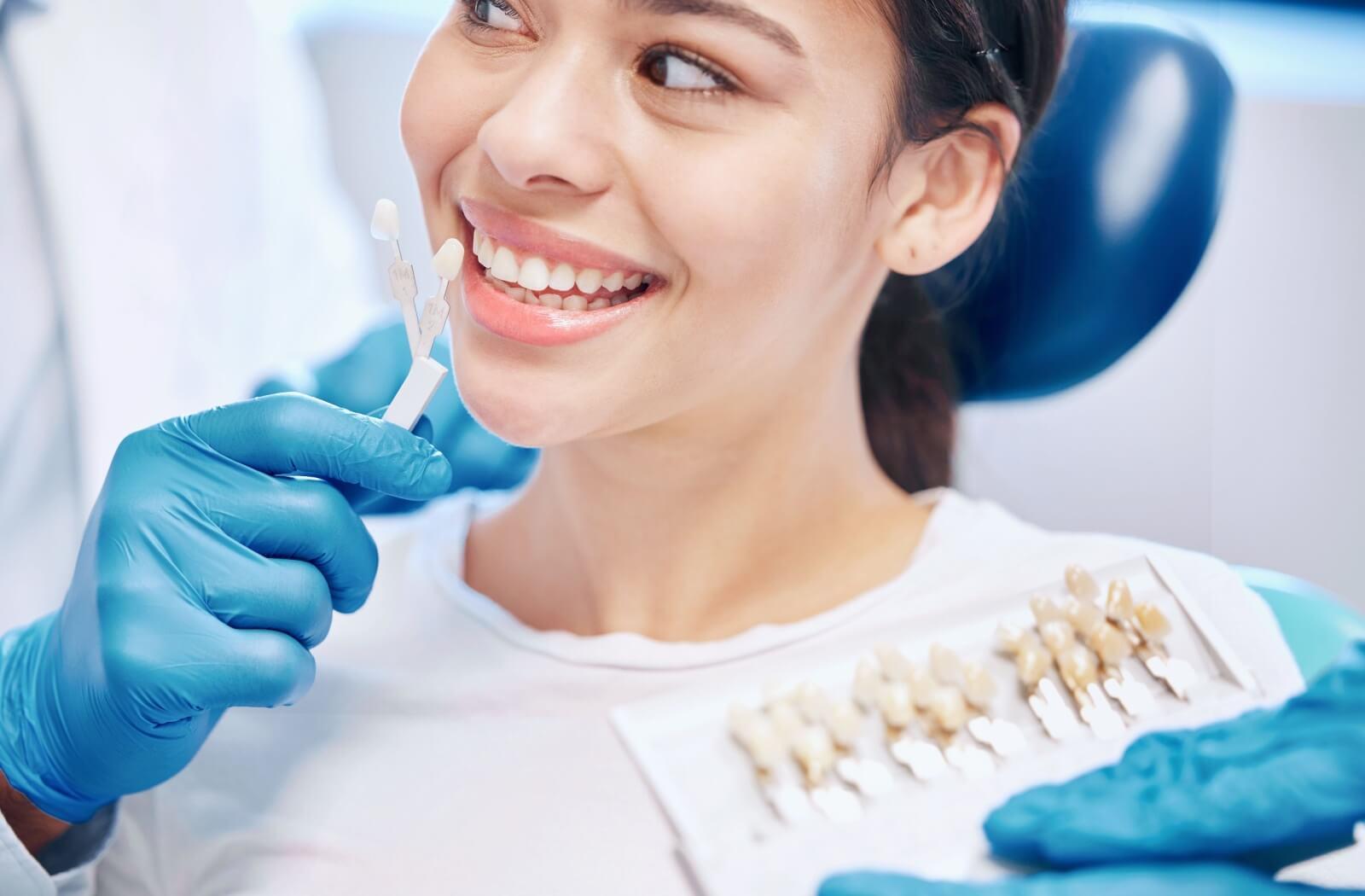 A person being fitted for the right colour dental crown to match their teeth
